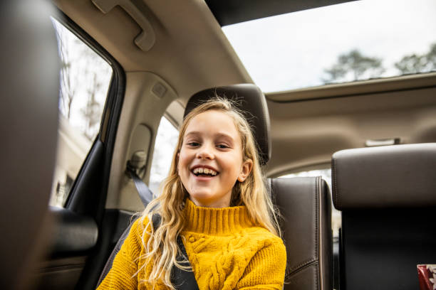 Tween girl laughing in back seat of automobile